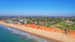 An aerial view of a coastal town with a beach, residential areas, and green spaces. - Thymbra Villa, Vale do Lobo, Algarve (Vale do Lobo)