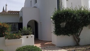 A white building with a curved facade, a small arched entrance, and a tree in the foreground. - Thymbra Villa, Vale do Lobo, Algarve (Vale do Lobo)