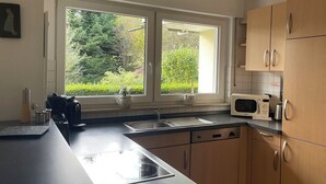 A kitchen with two windows, a microwave, and wooden cabinets. - Beautiful vacation apartment "Karl May" in Elspe/Sauerland, approx. 65 sqm, for 1-4 persons (Lennestadt)