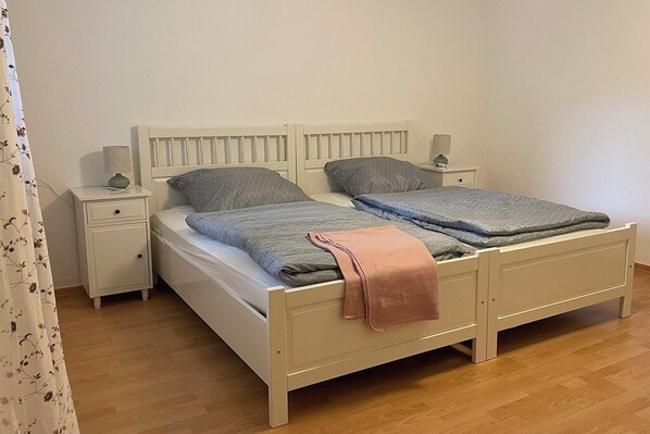 Un lit double avec une tête de lit, deux tables de chevet et une petite table à poser près du lit.