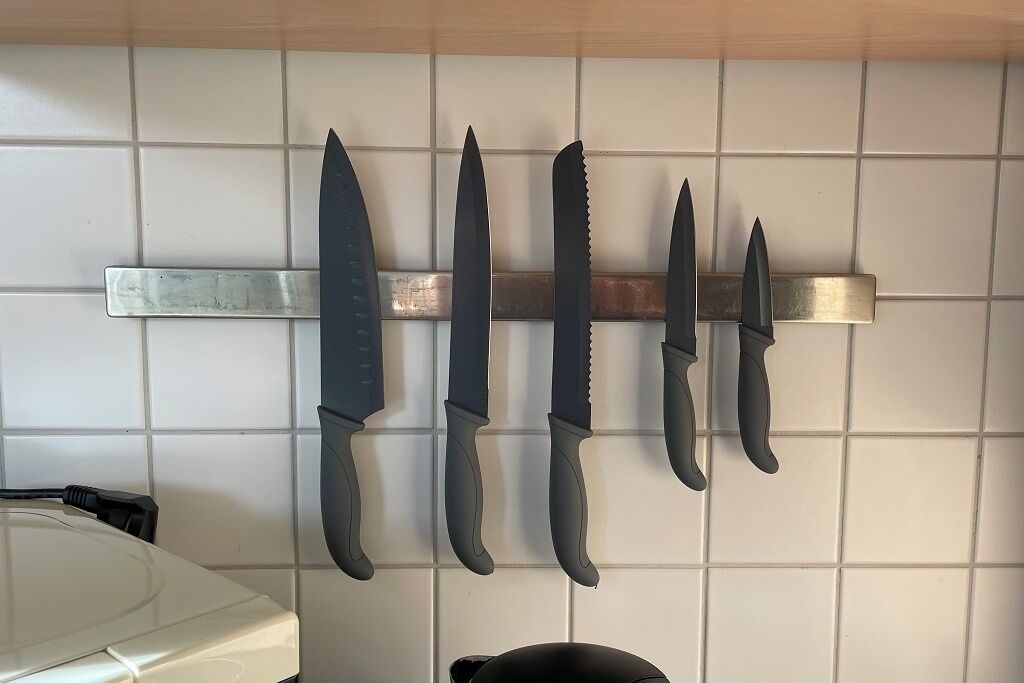 Una cocina con un soporte para cuchillos que contiene cinco cuchillos.
