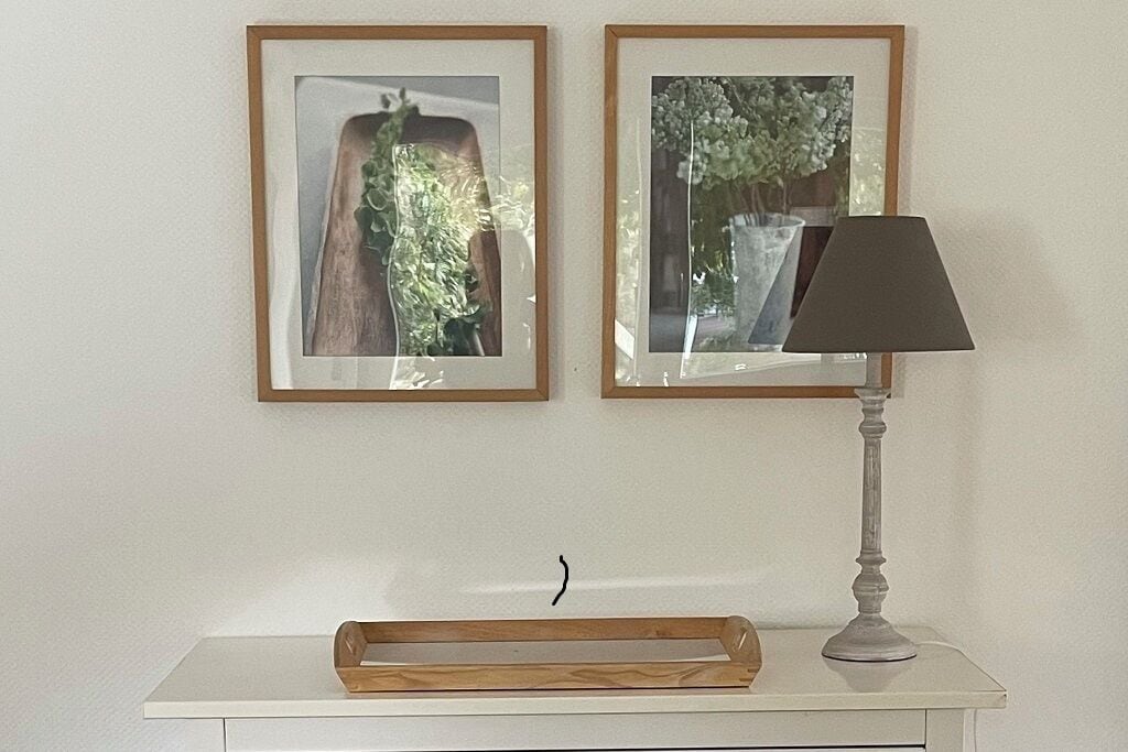 Ein wei ßer Tisch mit zwei gerahmten Bildern, einer Lampe und einer Holztablett.