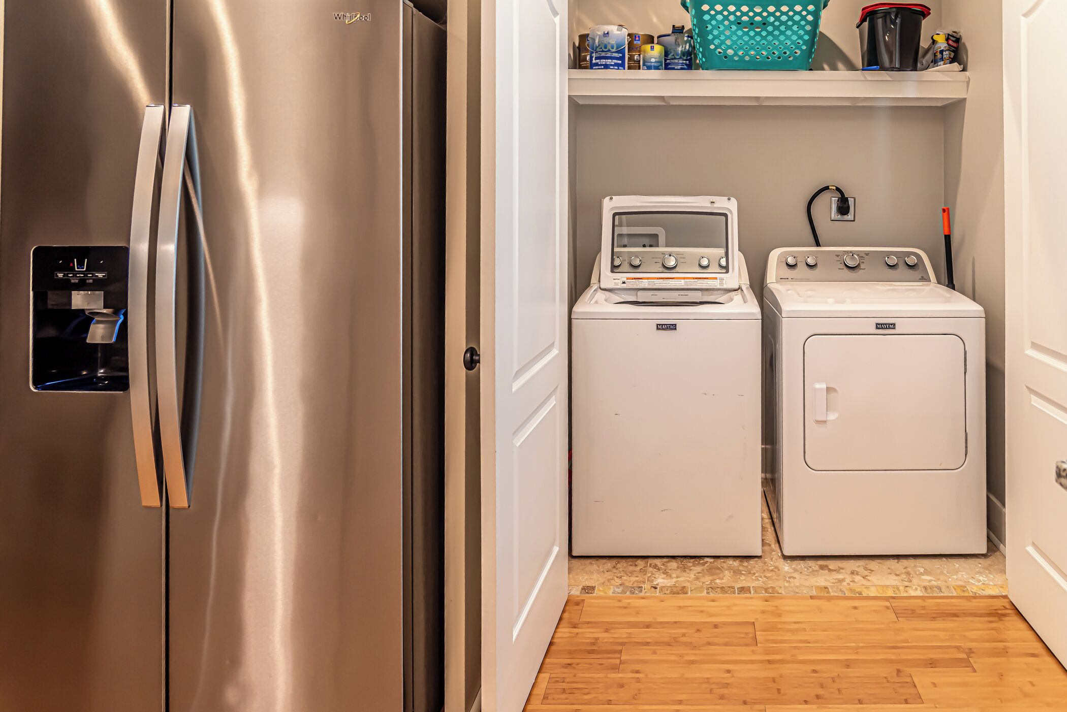 A compact laundry room with a stainless steel refrigerator, a washing machine, and a dryer.