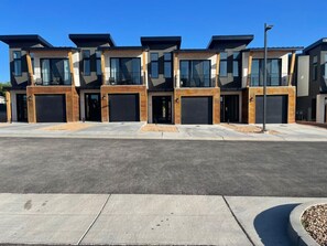 A row of modern, multi-story residential buildings with large windows and garage doors.