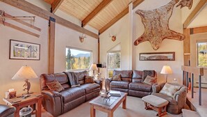 A spacious living room with leather sofas, wooden coffee table, and a large fur rug.