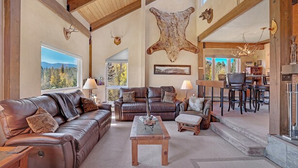 A spacious living room with leather sofas, a wooden coffee table, and a large wall-mounted animal hide.
