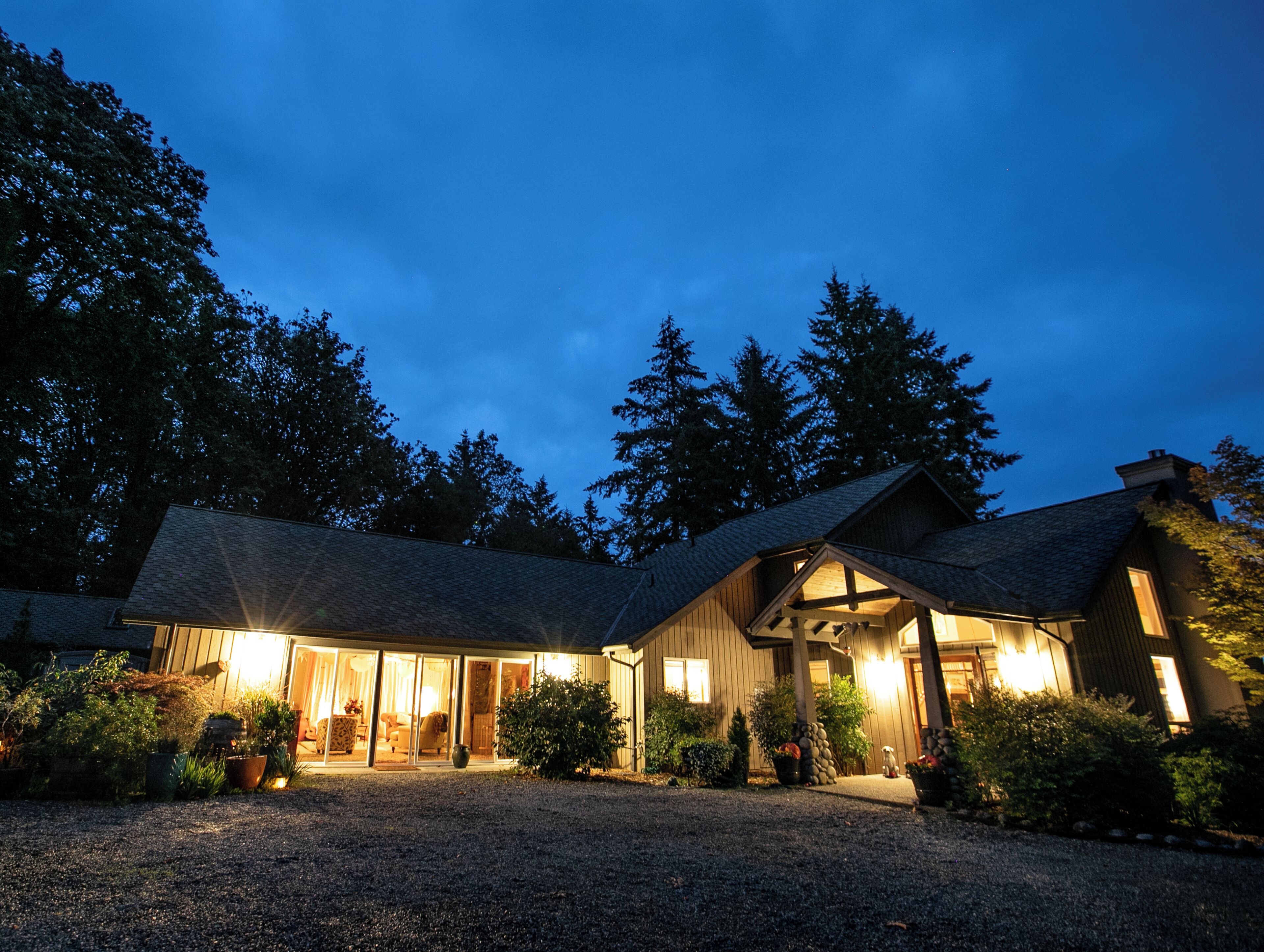 Une maison avec une allée en gravier, un revêtement extérieur en bois et une entrée bien éclairée.