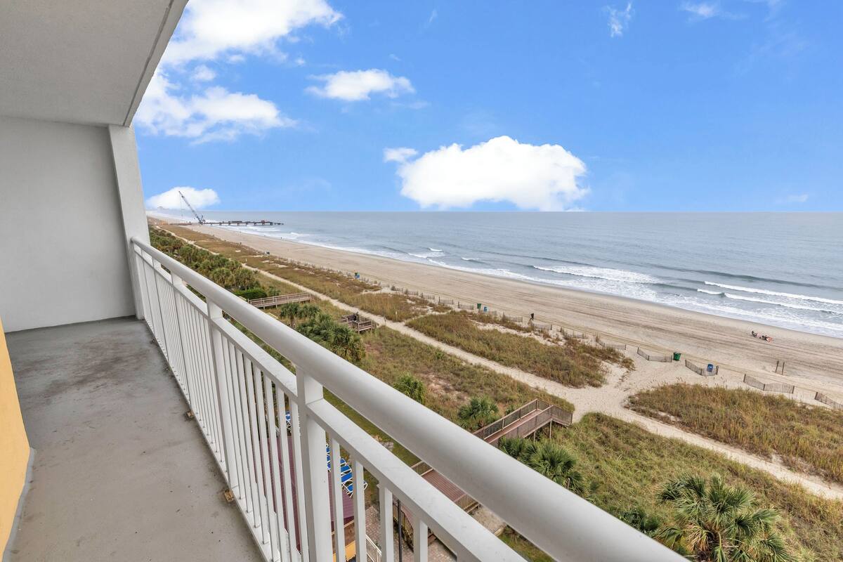 Un balcon avec vue sur une plage et l’océan.