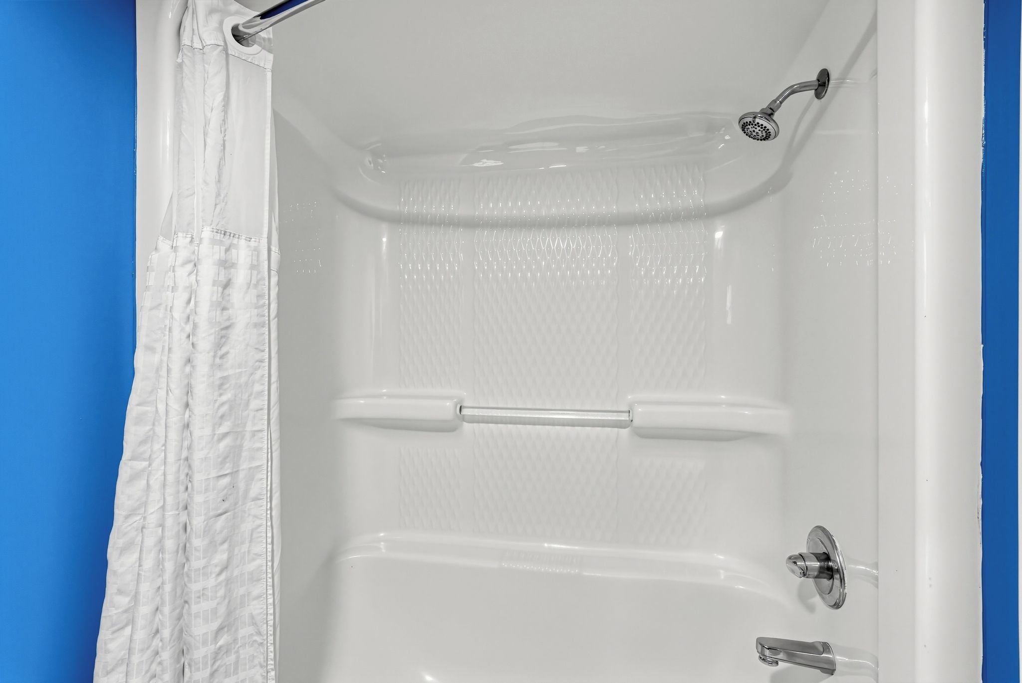 Una bañera blanca con cabezal de ducha, toallero y grifo.