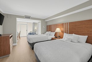 Habitación de hotel con dos camas, un escritorio, una silla, una lámpara y vistas al exterior.