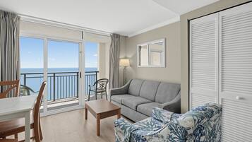 A balcony with a view of the sea, a sofa, a table, and a chair.