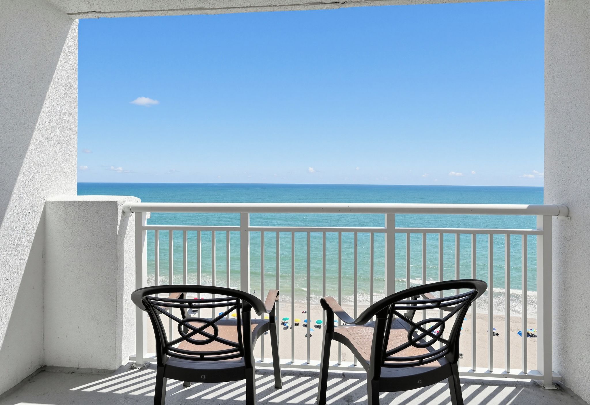 Un balcon avec deux chaises donnant sur une plage.