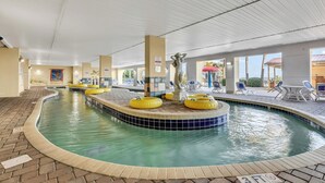 An indoor swimming pool with yellow floating rings, a statue, and a tiled edge. - Camelot By the Sea (Myrtle Beach)