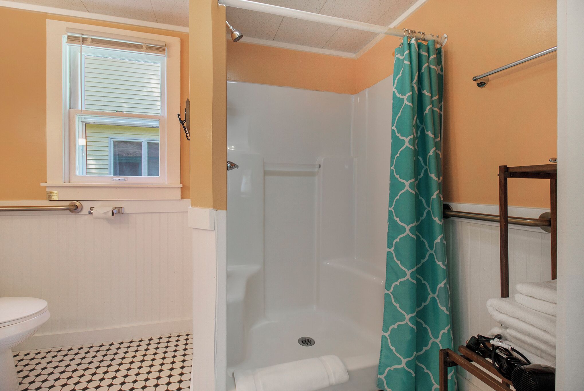 A bathroom with a toilet, a shower with a glass door, and a towel rack.