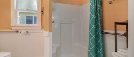 A bathroom with a toilet, a shower with a glass door, and a towel rack.