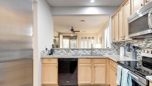 A modern kitchen with wooden cabinets, a dishwasher, a stainless steel stove, and a tiled backsplash. - Anthem Getaway with Backyard Oasis!  (New River)