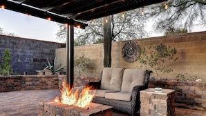 A patio with a fire pit, outdoor furniture, and decorative wall art. - Anthem Getaway with Backyard Oasis!  (New River)