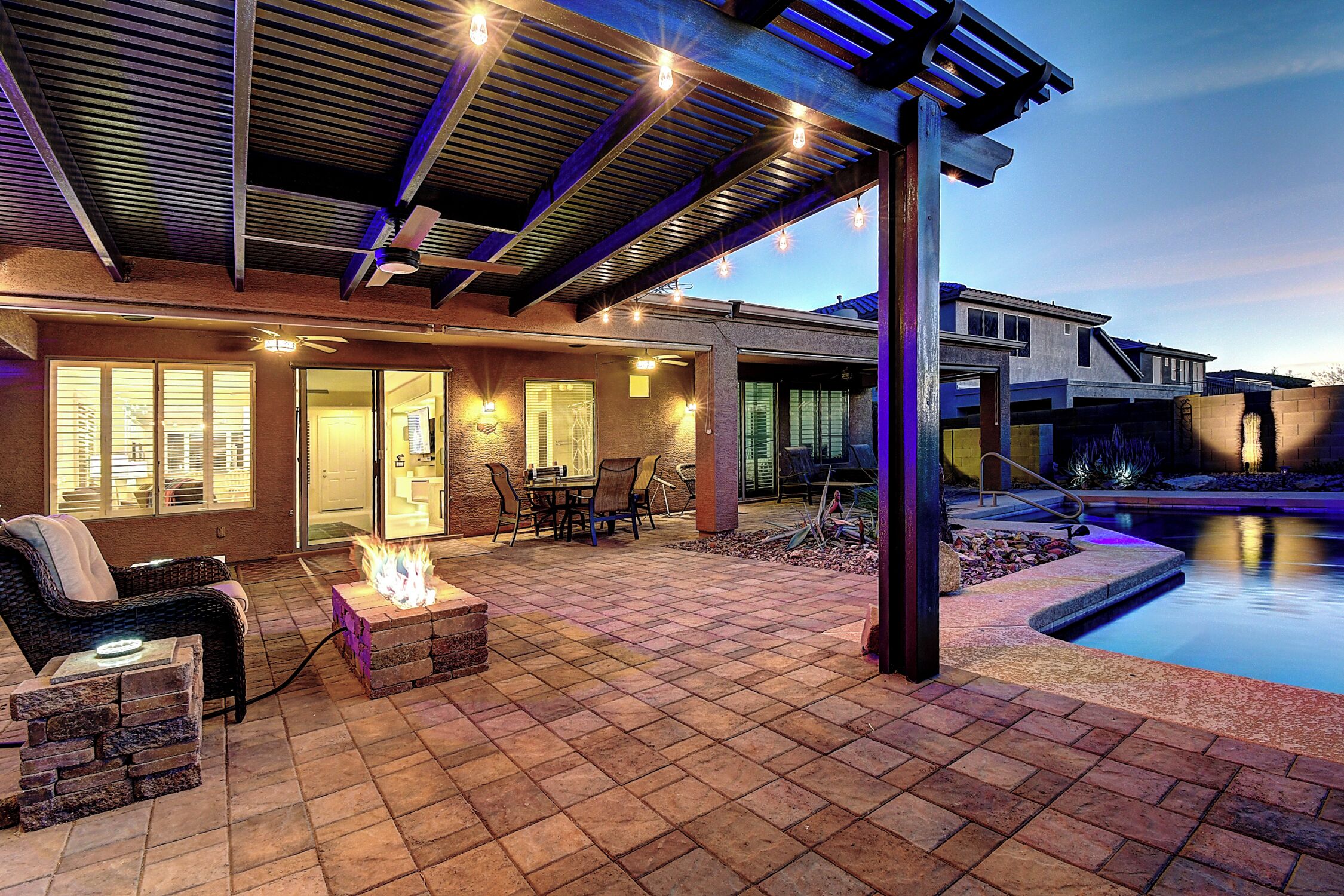 A patio with a fire pit, outdoor furniture, and a swimming pool.