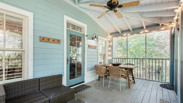 A covered porch with wicker furniture, a ceiling fan, and string lights. - The Grey Gull (Panama City Beach)
