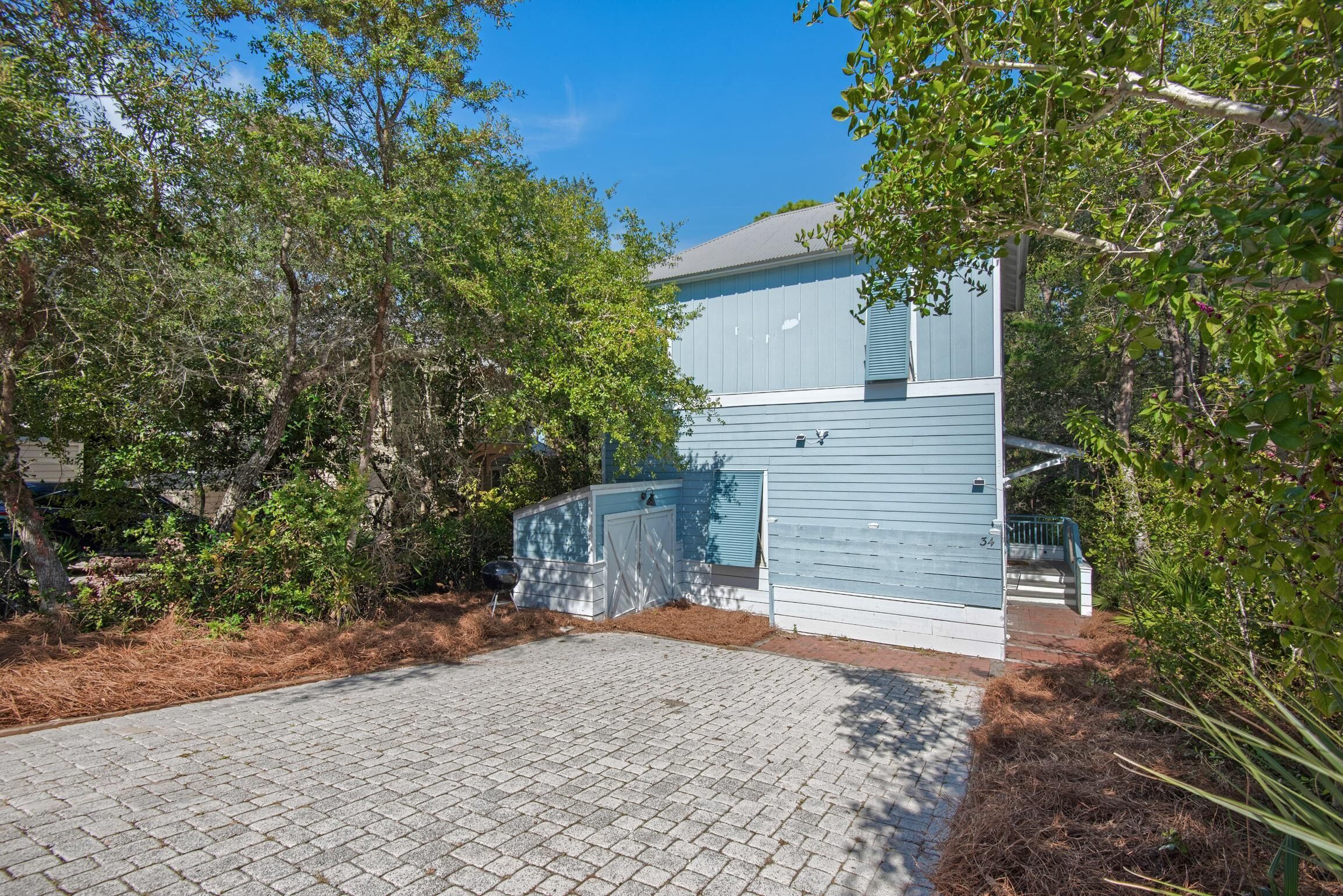 A two-story building with a blue exterior, a paved driveway, and a gated entrance.