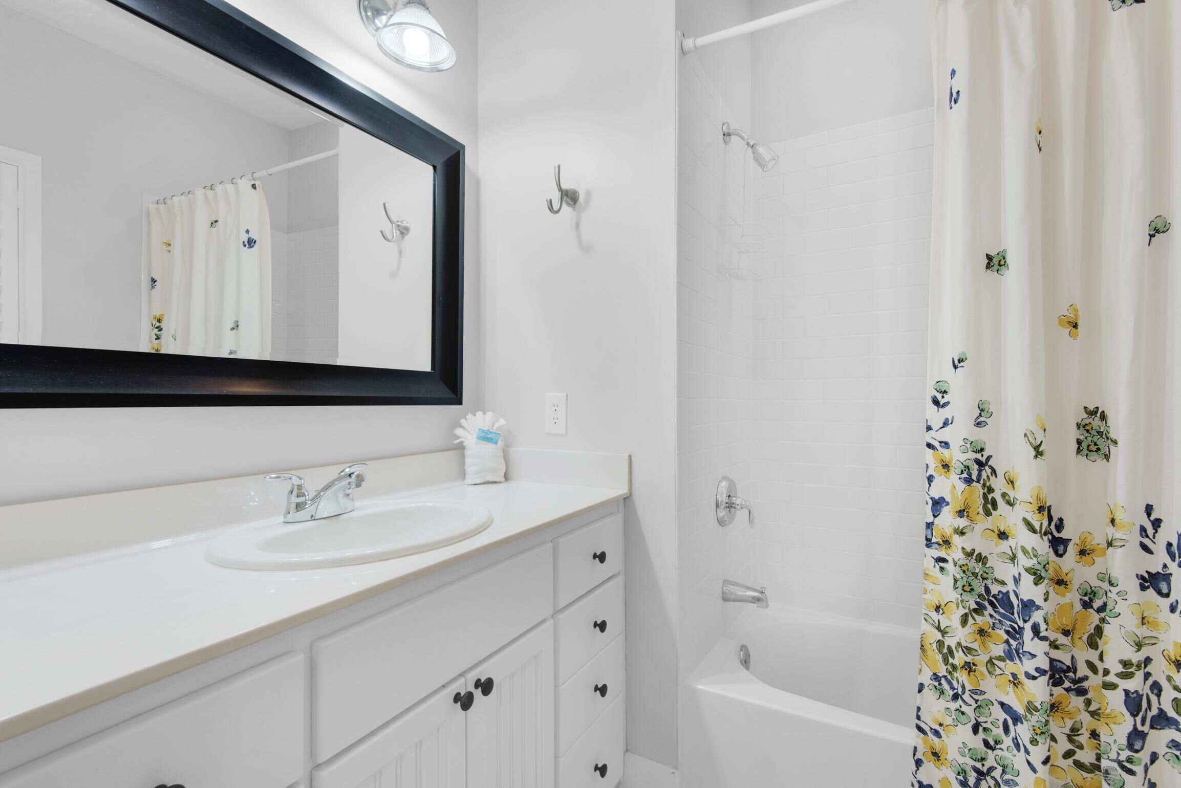 A bathroom with a white sink, mirror, and bathtub.