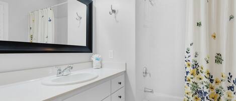 A bathroom with a white sink, mirror, and bathtub.