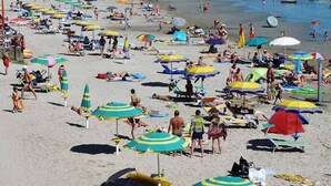 A crowded beach with numerous umbrellas and people sunbathing.