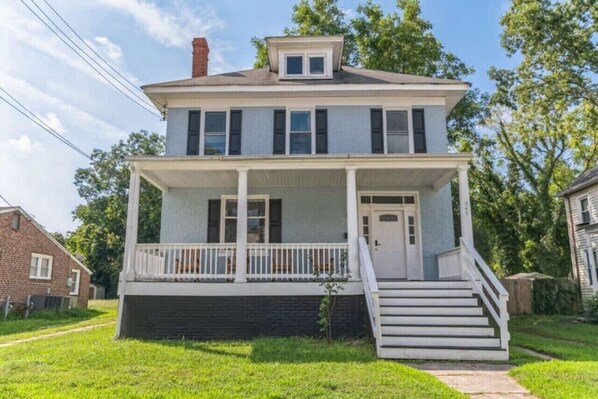 A two-story house with a front porch, a small front yard, and a brick garage. - 2 homes that sleep 16! (Hampton)