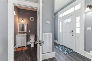 A modern bathroom with a white vanity, toilet, and a mirror. - 2 homes that sleep 16! (Hampton)