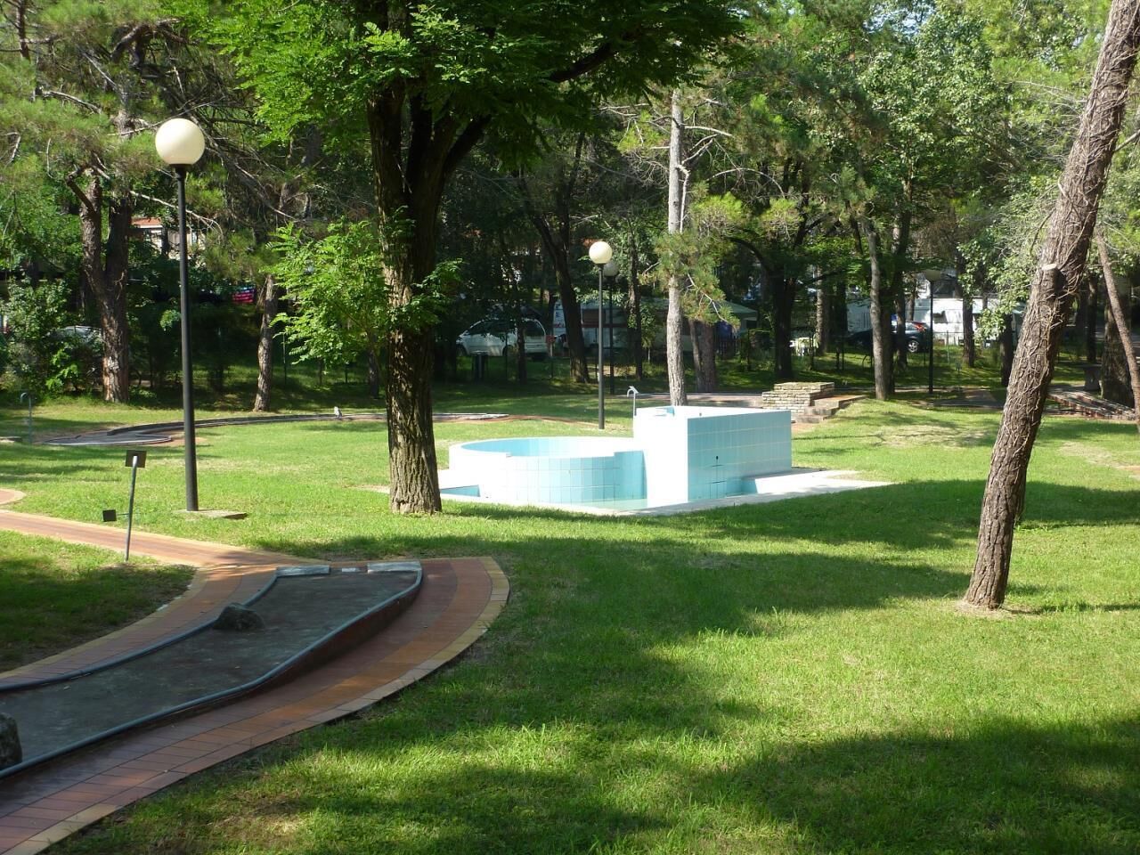 Un parc avec un chemin pavé, des arbres et une structure bleue.