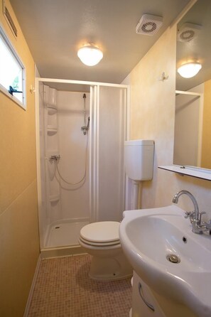 Une petite salle de bain comprenant une douche, des toilettes et un lavabo.