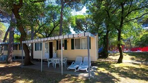 A small, single-story structure with a covered porch, outdoor seating area, and a table.