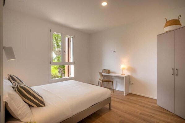 A bedroom with a bed, a desk, and a wardrobe.