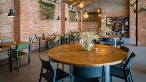 Un restaurante con paredes de ladrillo, focos colgantes y diversas opciones de asientos, incluyendo mesas redondas y bancos.
