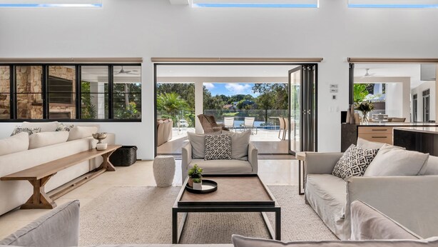 A modern living room with a sofa, coffee table, and a view of an outdoor pool area. - Villa 8 The Lakes moments from pristine beaches, world-class golf courses, and the stunning Mt. Cool (Mount Coolum)