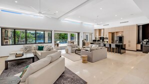 A spacious living area with a large window, a kitchen with modern appliances, and a dining area. - Villa 8 The Lakes moments from pristine beaches, world-class golf courses, and the stunning Mt. Cool (Mount Coolum)