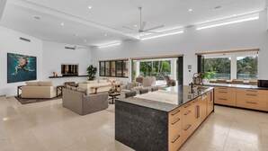 A spacious living area with a large sofa set, a dining table, and a kitchen with a marble island. - Villa 8 The Lakes moments from pristine beaches, world-class golf courses, and the stunning Mt. Cool (Mount Coolum)