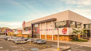 A modern building with a parking lot, a clear sky, and a sign for 'San Nicolás'.