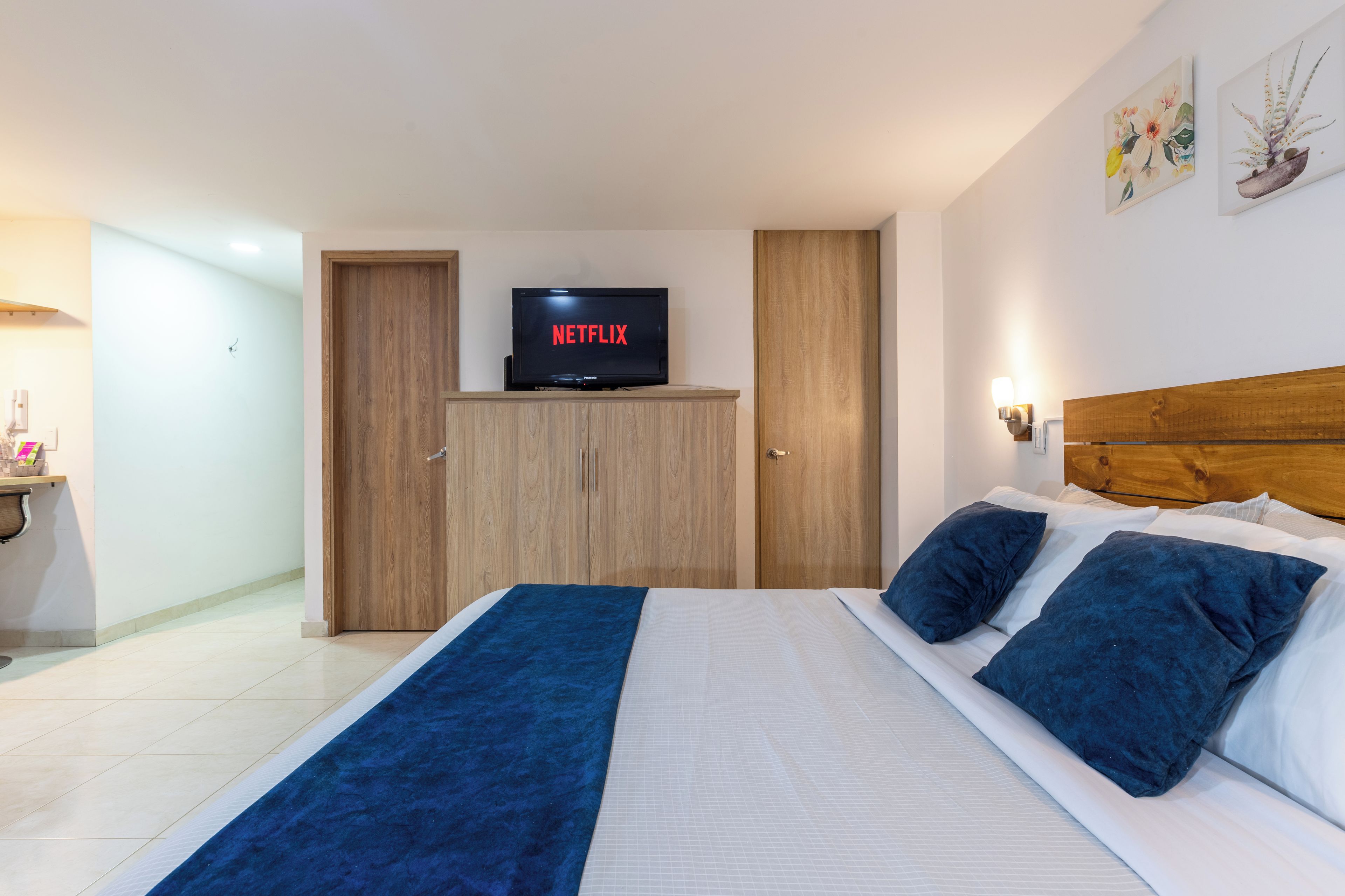 Une chambre d’hôtel avec un lit, un téléviseur affichant le logo « NETFLIX », et une armoire en bois.