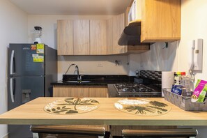 Una cocina compacta con refrigerador, estufa y gabinetes de madera.