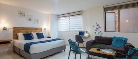Un dormitorio moderno con cama, escritorio y sofá.