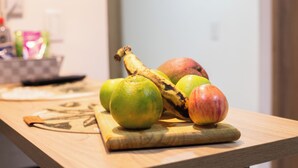 A wooden cutting board with fruits on a kitchen counter.