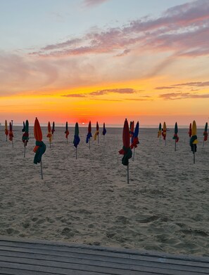 Une plage bordée de rangées de parasols et d’une promenade en bois.