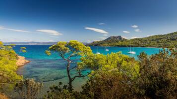 A coastal landscape with clear turquoise waters, boats, and lush greenery.