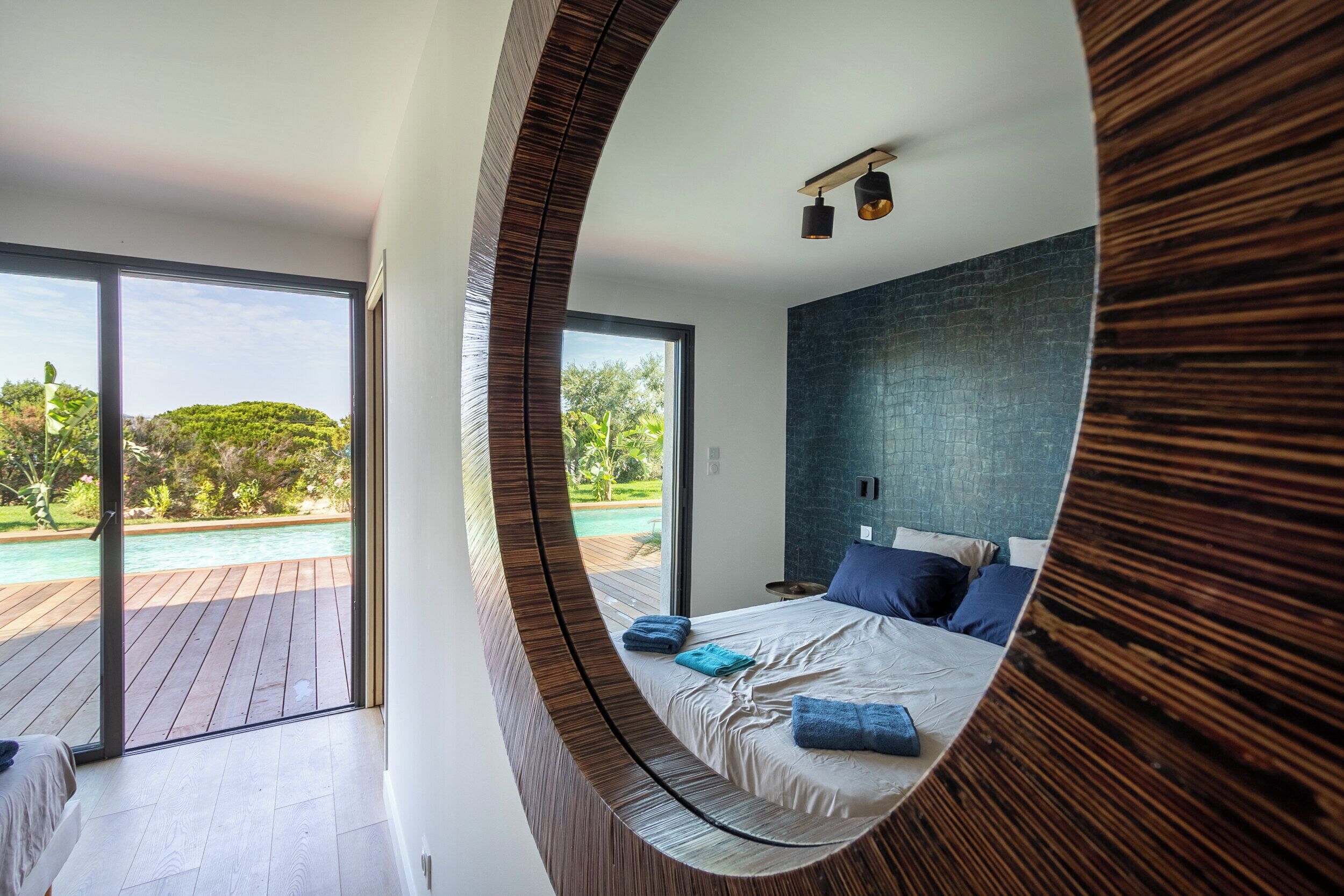 Une chambre avec un grand lit, une vue sur une piscine et une terrasse en bois.