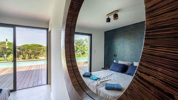 Une chambre avec un grand lit, une vue sur une piscine et une terrasse en bois.