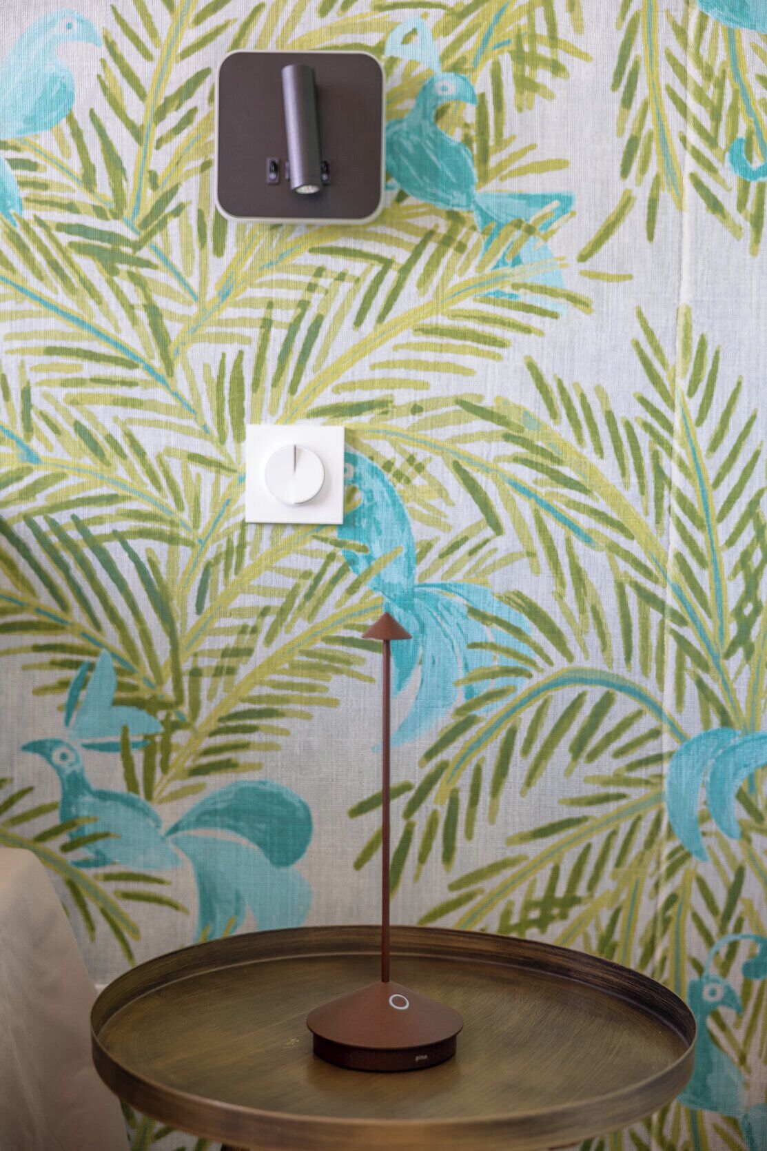 A room with a round wooden table, a wall-mounted light switch, and a power outlet.