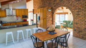 A kitchen with wooden cabinets, a brick wall, and a dining area with a wooden table and chairs.