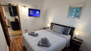 A hotel room with a bed, two bedside tables, a TV, and a window. - Arcade Room + Fire Pit + Creek Views | Near Waterparks (Wisconsin Dells)