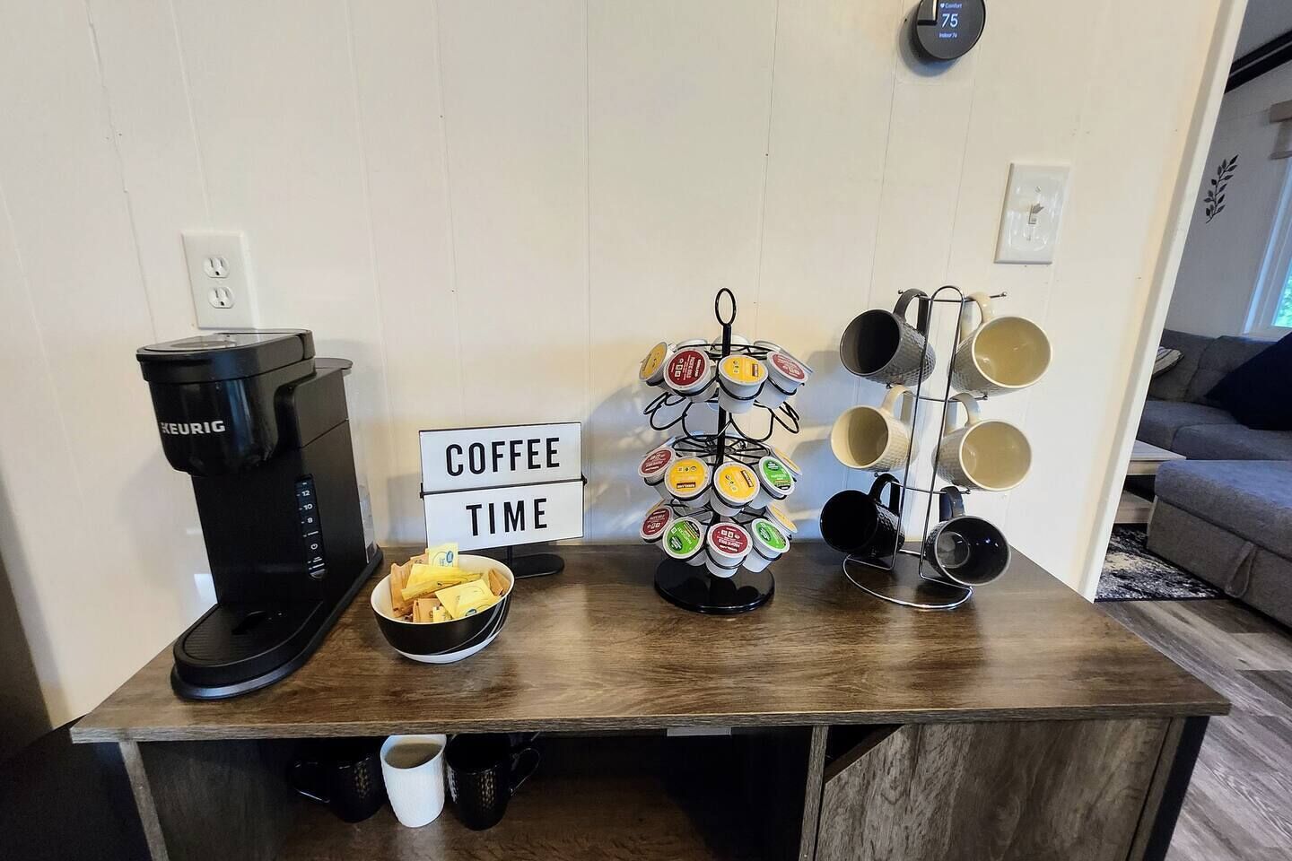 A coffee station with a Keurig machine, a coffee pod holder, a bowl of coffee pods, and a sign that reads 'COFFEE TIME'.